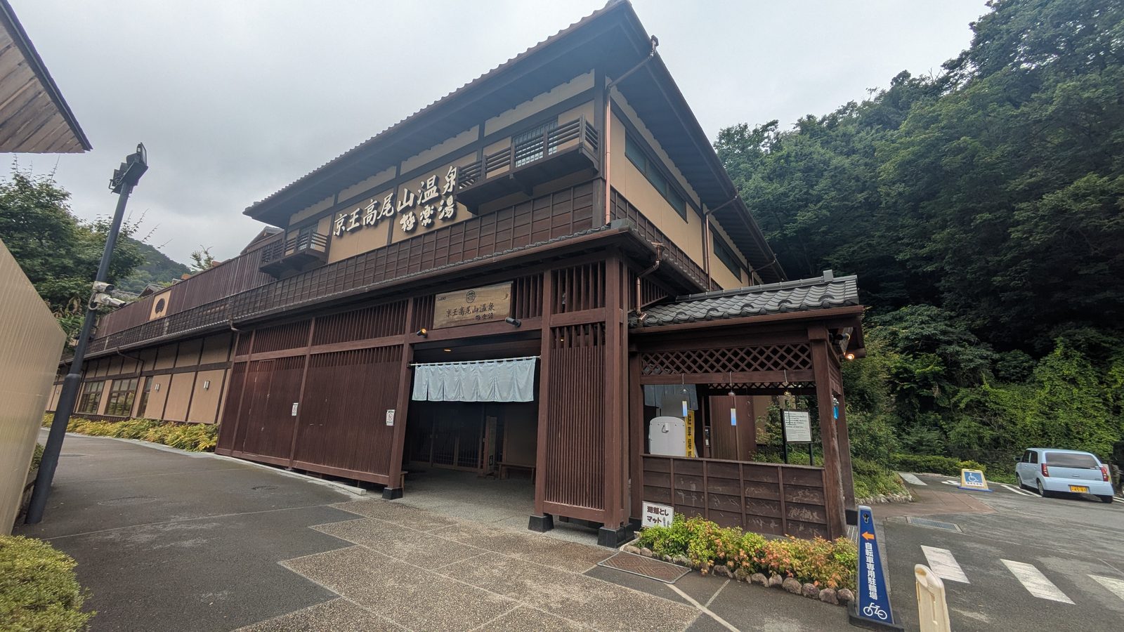 The wooden exterior of Keio Takaosan Onsen Gokurakuyu next to the station