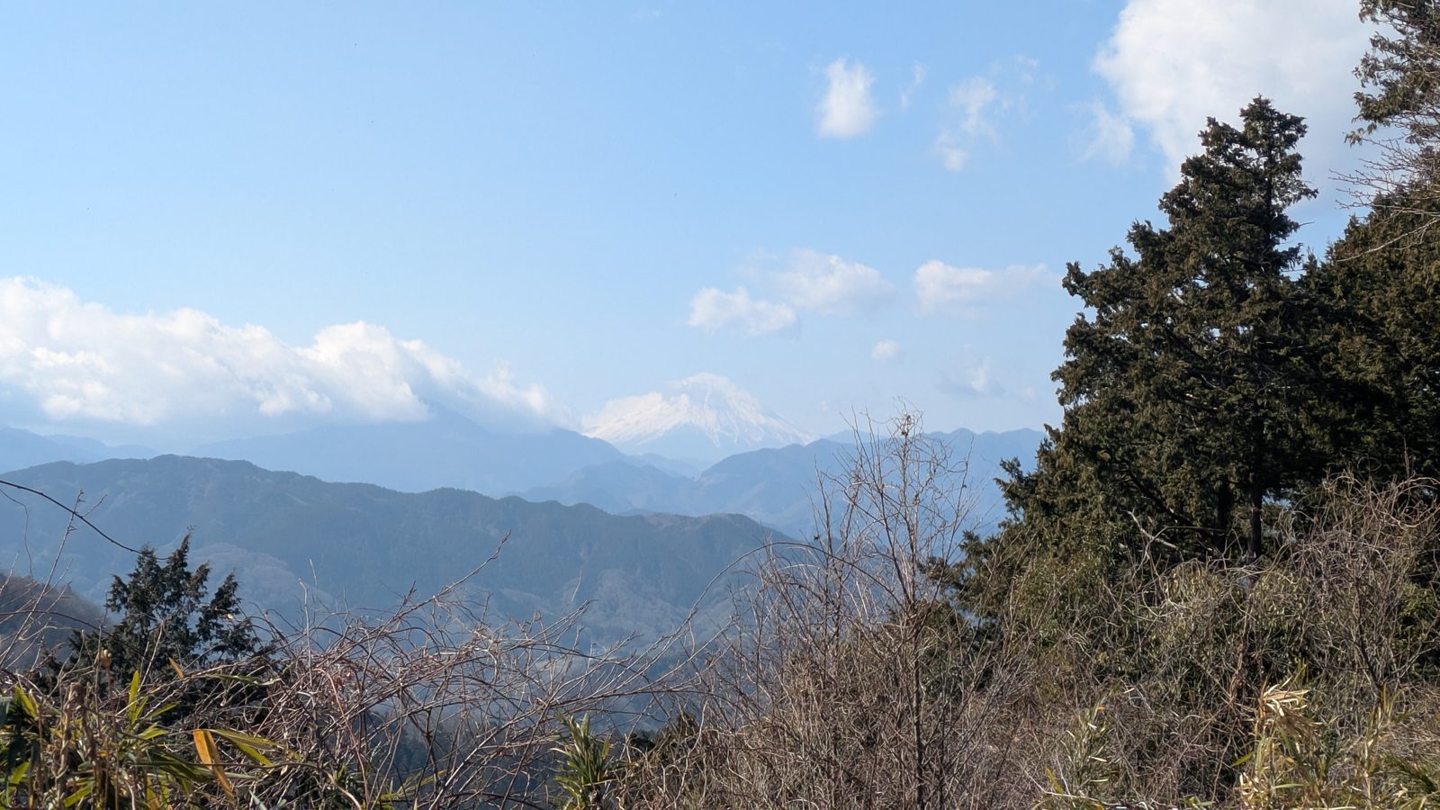 Snow-capped Mount Fuji seen across ridgelines from Mount Takao in winter