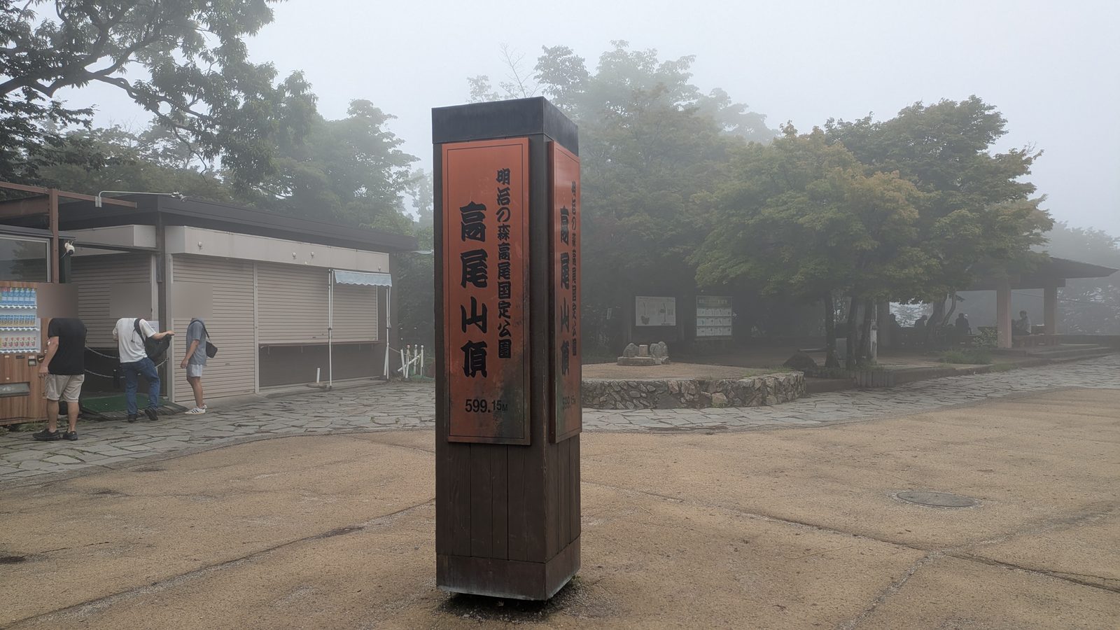 The summit marker post reading Mount Takao 599.15 m in mist