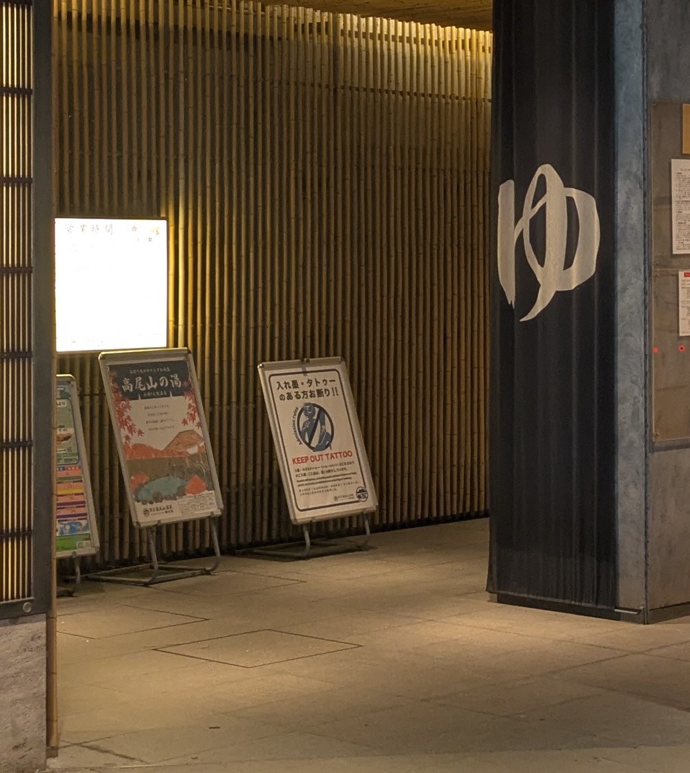 Standing signs inside the onsen entrance, one of them reading KEEP OUT TATTOO in red capitals