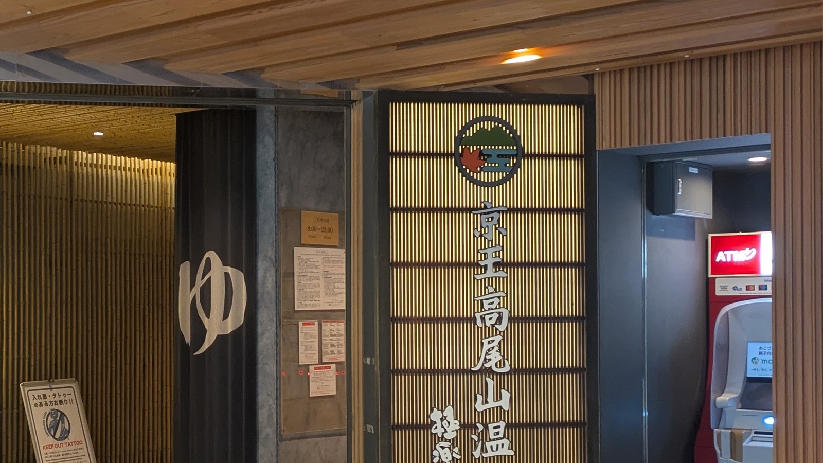 The entrance to Keio Takaosan Onsen at Takaosanguchi Station, a dark curtain hanging in a doorway