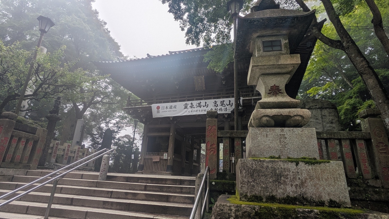The wooden Shitennomon Gate at Takao-san Yakuo-in, with a Japan Heritage banner hanging beneath the roof