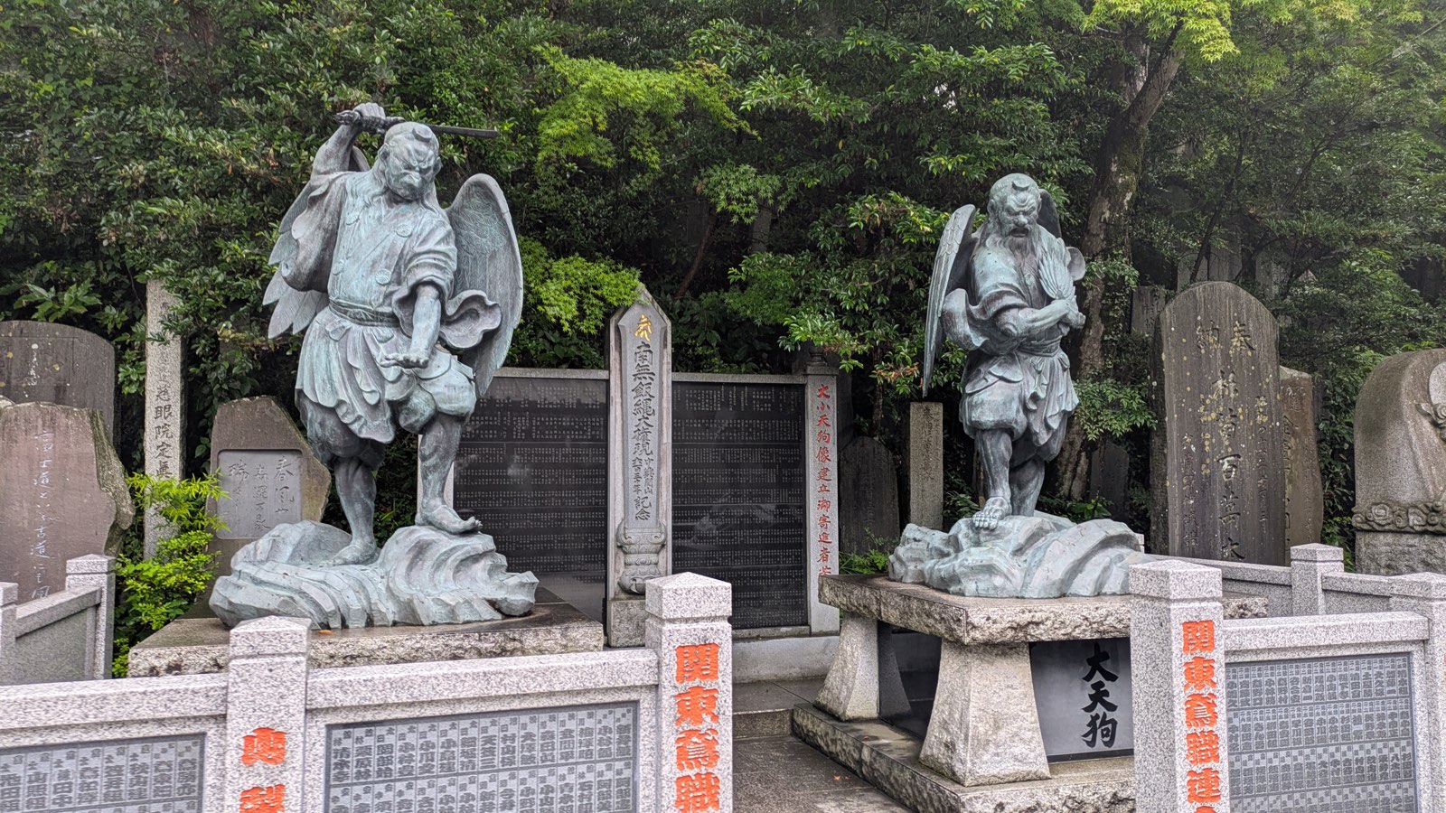Two bronze tengu statues at Yakuo-in, one long-nosed, one crow-billed, on stone pedestals