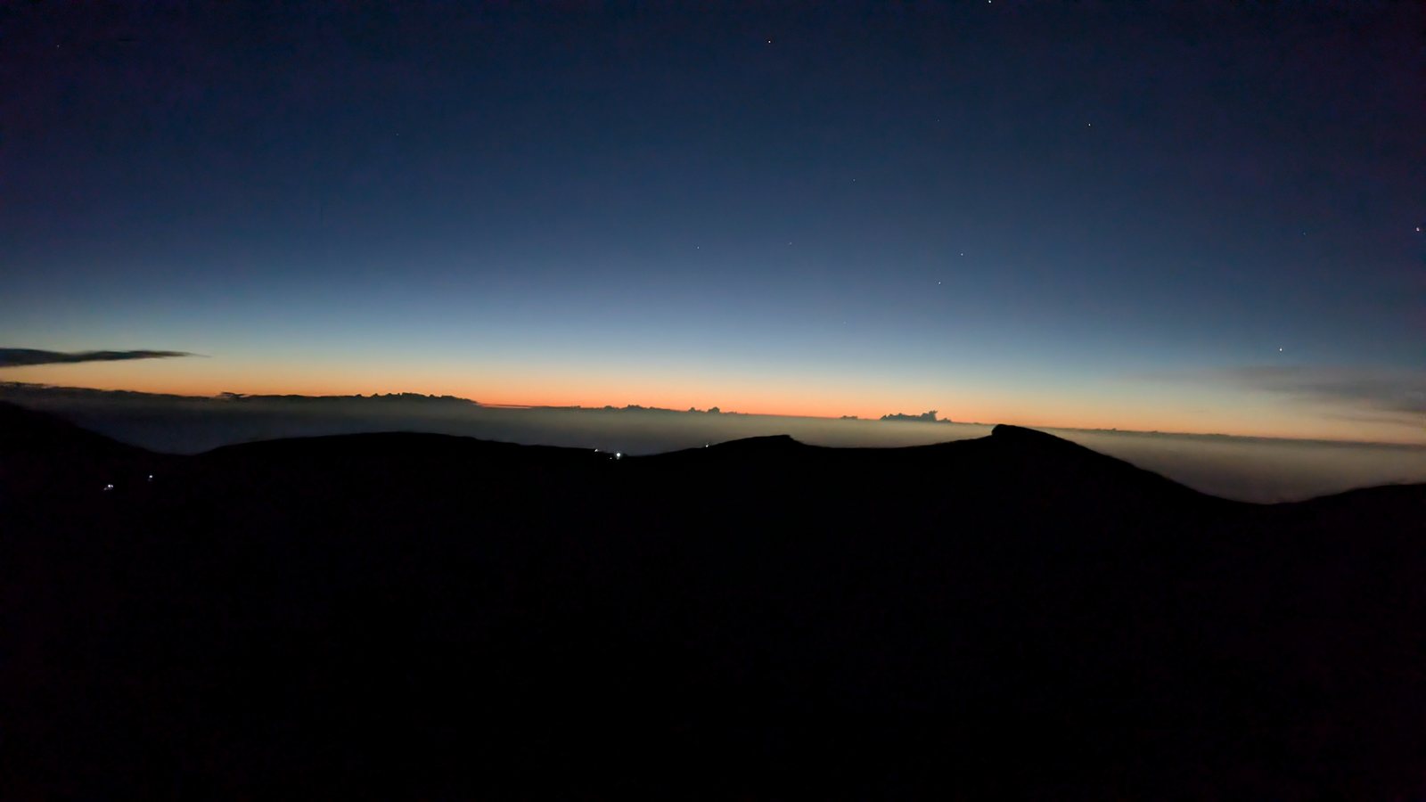 The crater rim in silhouette under a band of pre-dawn light