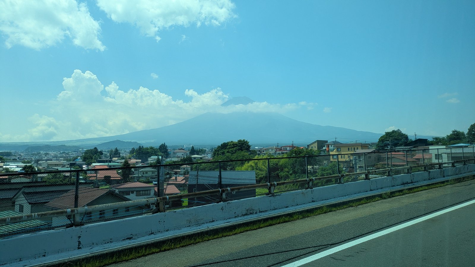Mount Fuji seen through a coach window above the roofs of a town