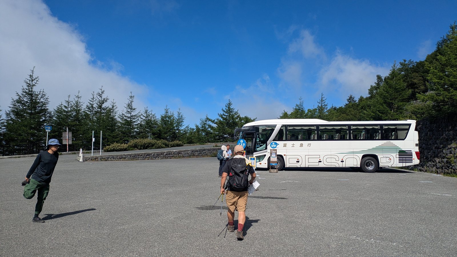 Hikers walking toward a bus in a car park at the Fujinomiya fifth station