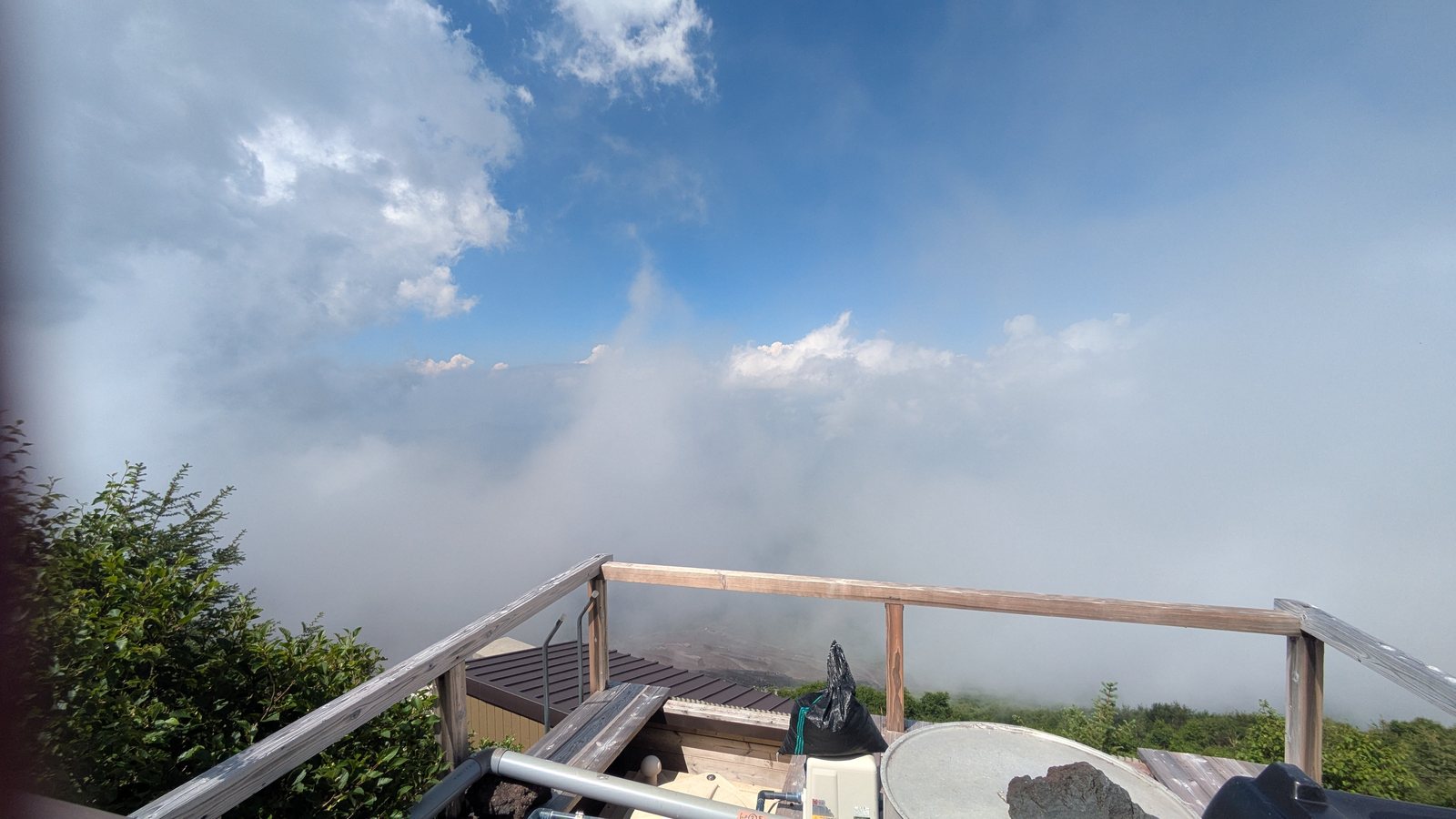 A wooden deck at a mountain hut looking out over a flat sea of cloud