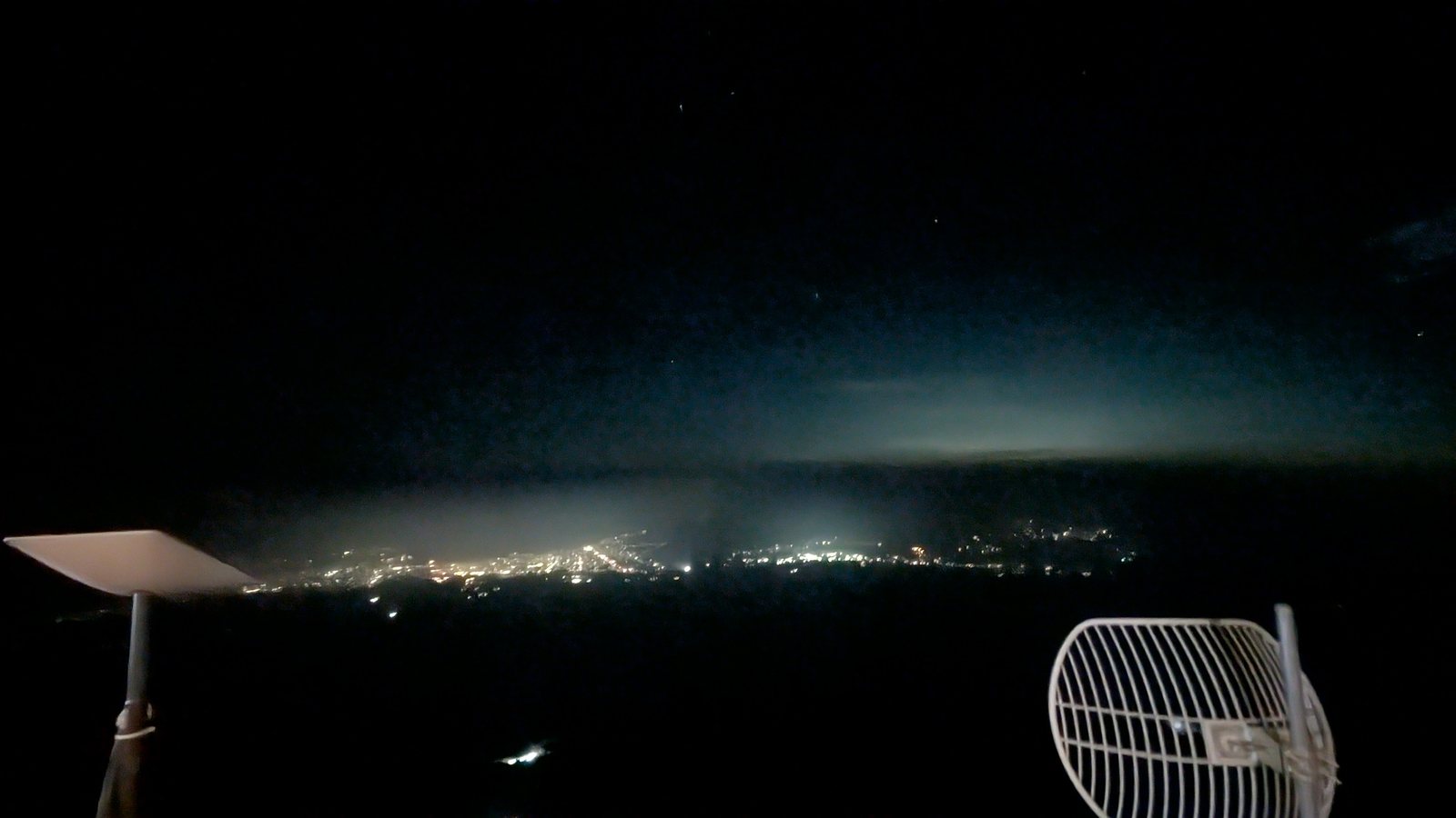 Town lights on the plain seen from a mountain hut in darkness