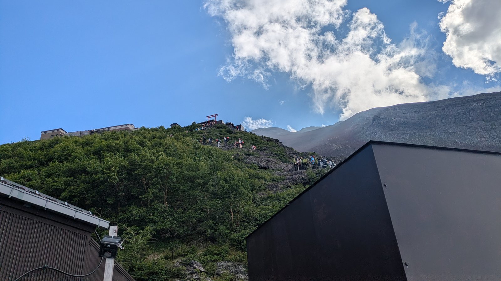 A steep zigzag trail above the hut with a red torii on the skyline