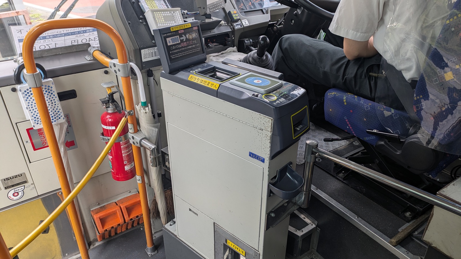 The fare box beside the driver of a Japanese bus with a note changer above it