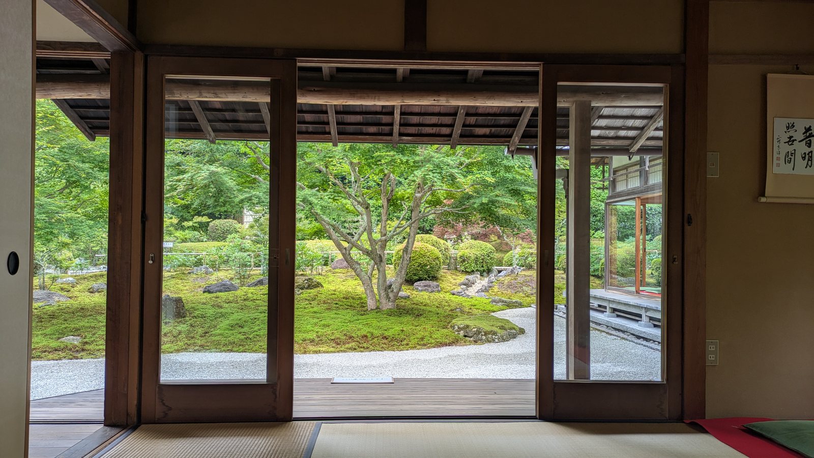 A tatami room with sliding doors open onto a green moss garden