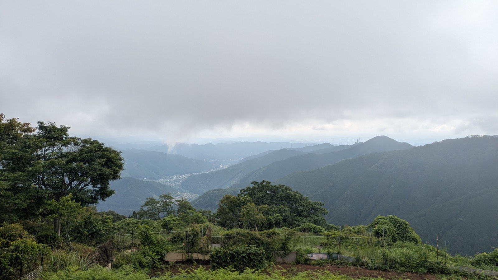 Ridges and a valley town under low cloud, seen from Fujimine above the cable car station on Mount Mitake