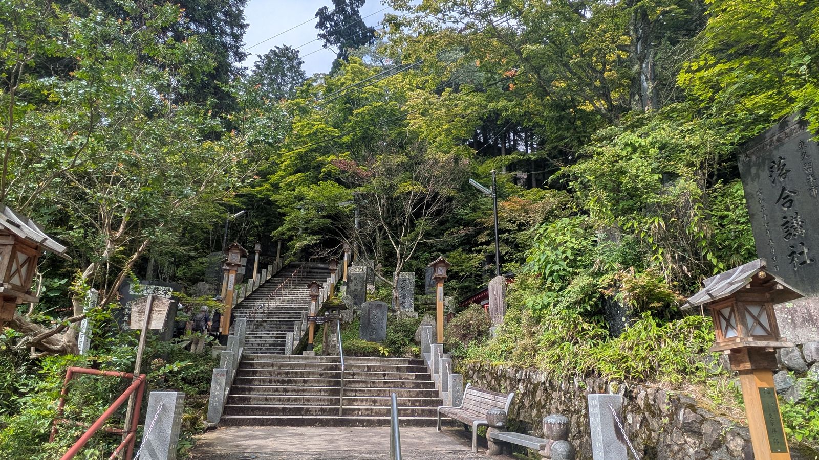 A long flight of stone steps climbing into trees with stone lanterns on both sides