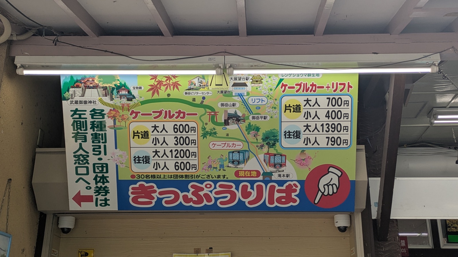 A large illustrated fare board above a ticket window showing cable car prices in Japanese