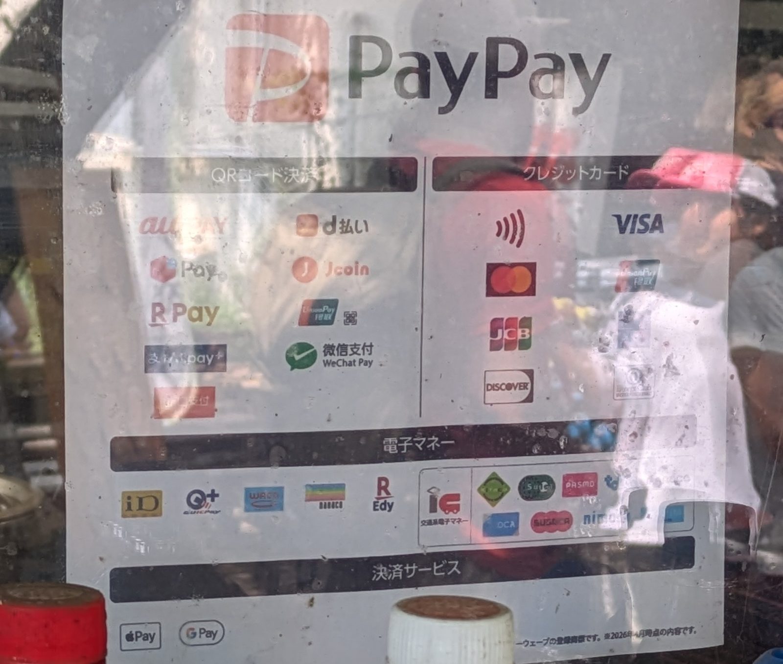 A payment acceptance sticker in a shop window showing dozens of cashless payment logos