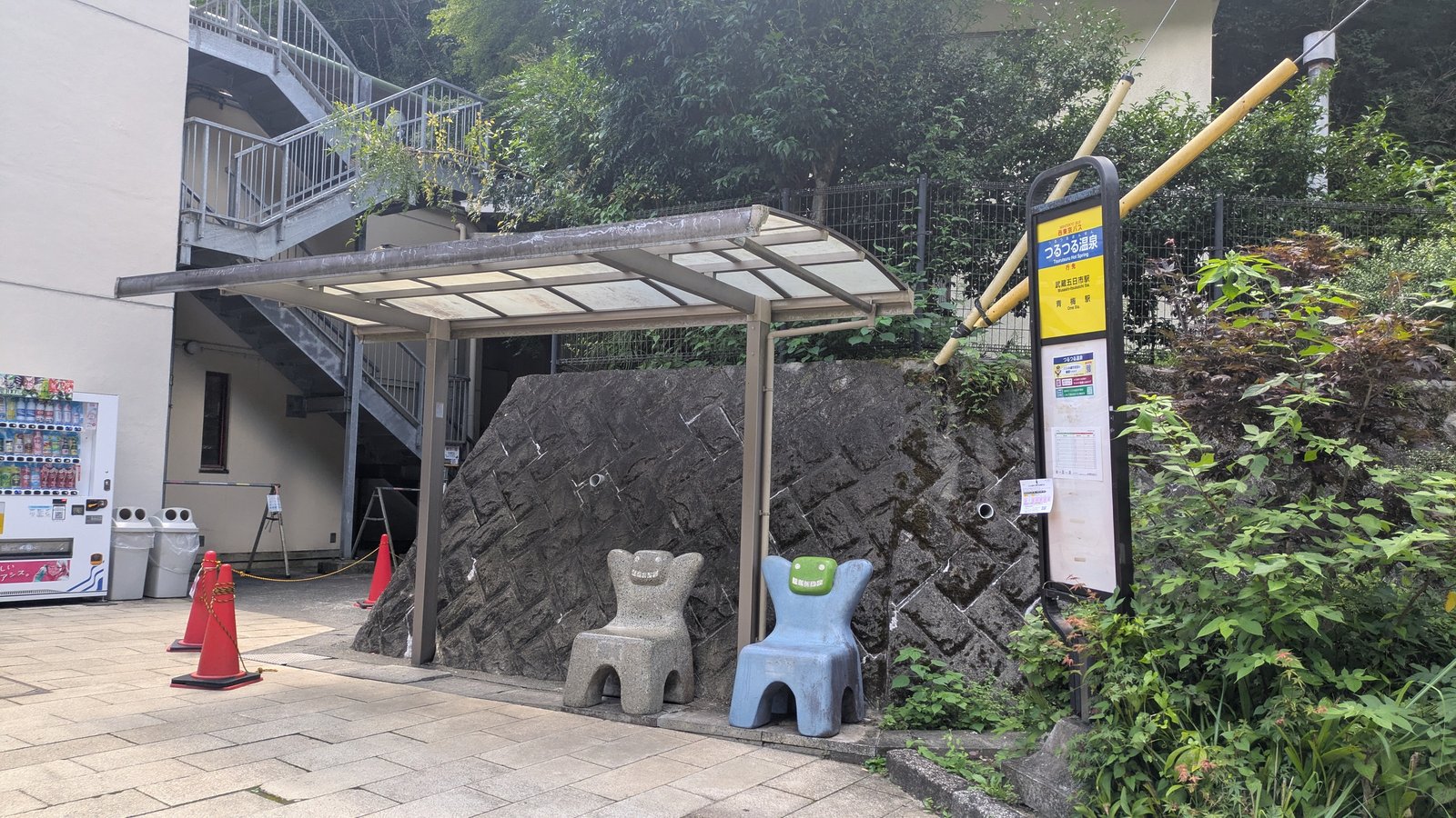 A bus shelter beside a road with a Nishi Tokyo Bus stop pole showing destinations in Japanese and English