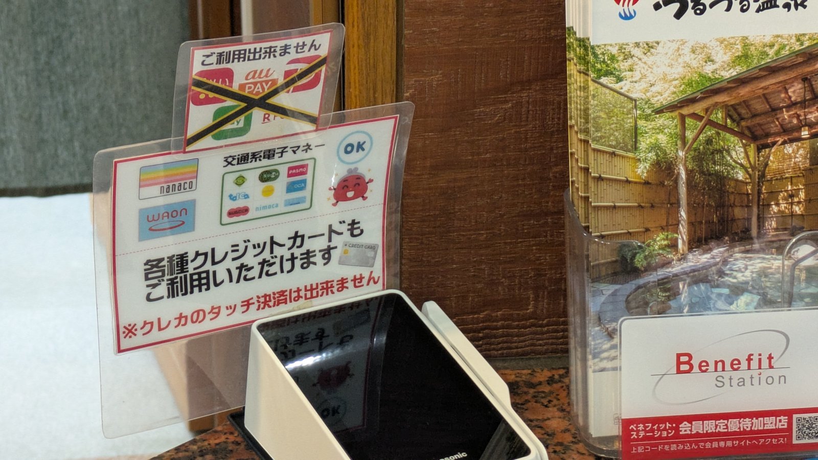 A laminated notice at a reception counter showing accepted electronic money and a red warning about contactless credit cards