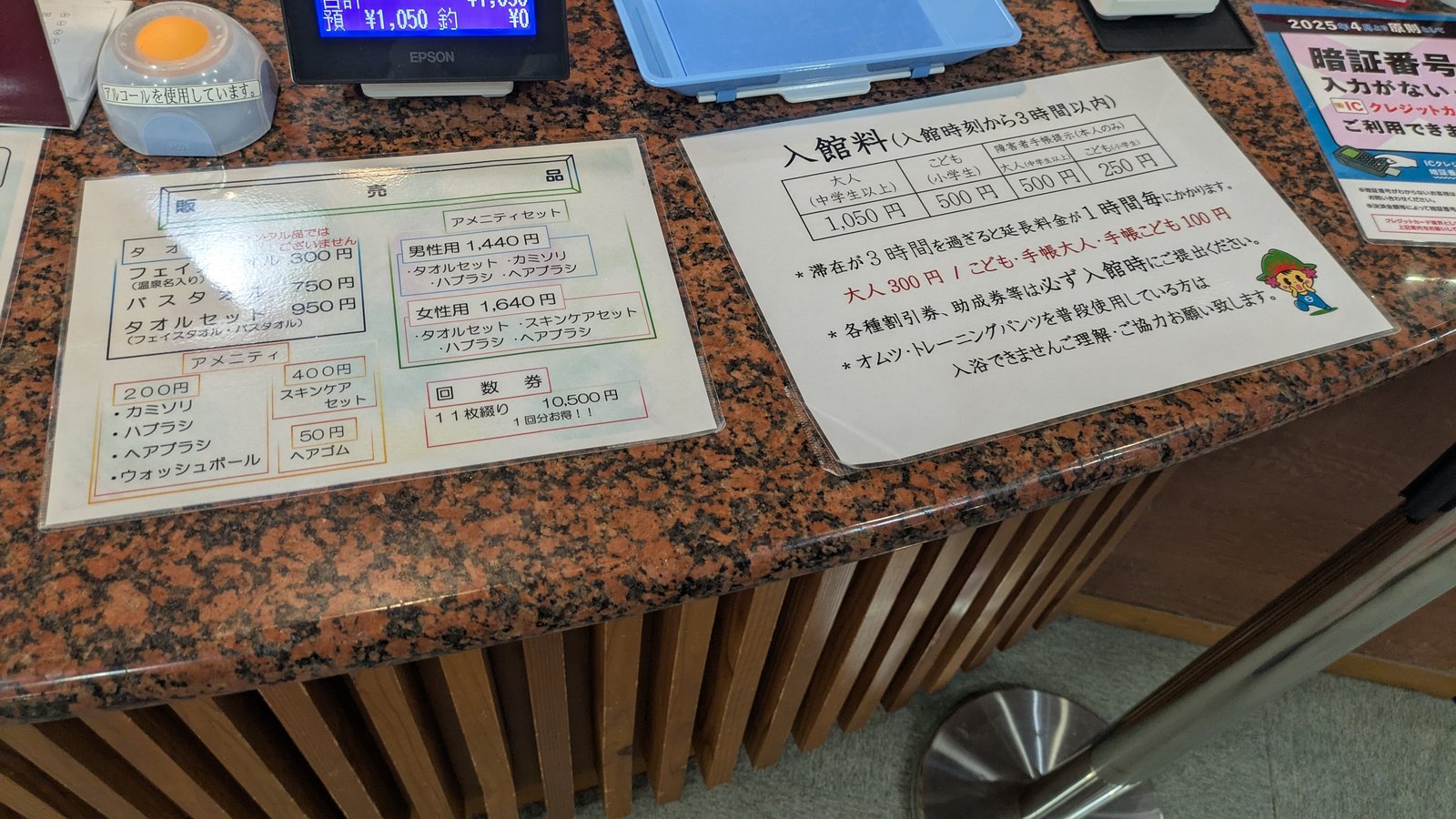 A printed price list for towels and toiletries at a bathhouse counter