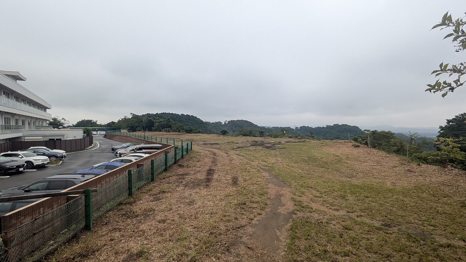 A car park and mown grass of a golf course seen from the trail just past the summit