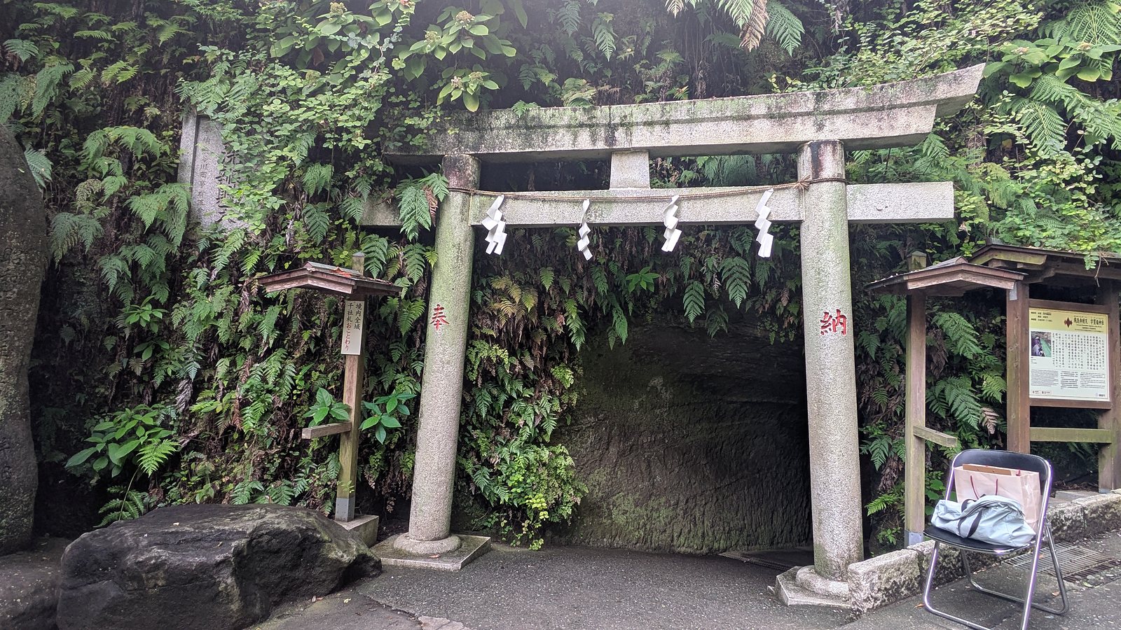 A stone torii in front of a tunnel cut through a rock face