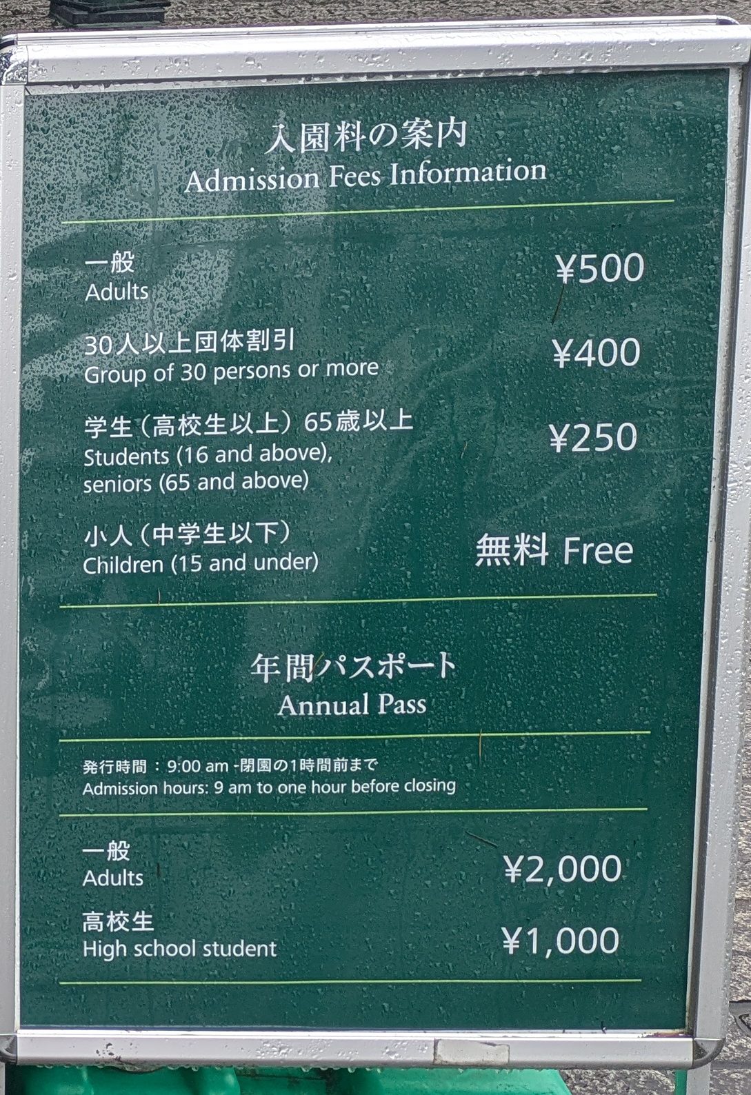 A bilingual green board listing admission at 500 yen for adults, with annual passes at 2,000 yen